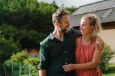 A homeowner couple smiling outside with energy efficient home in the background