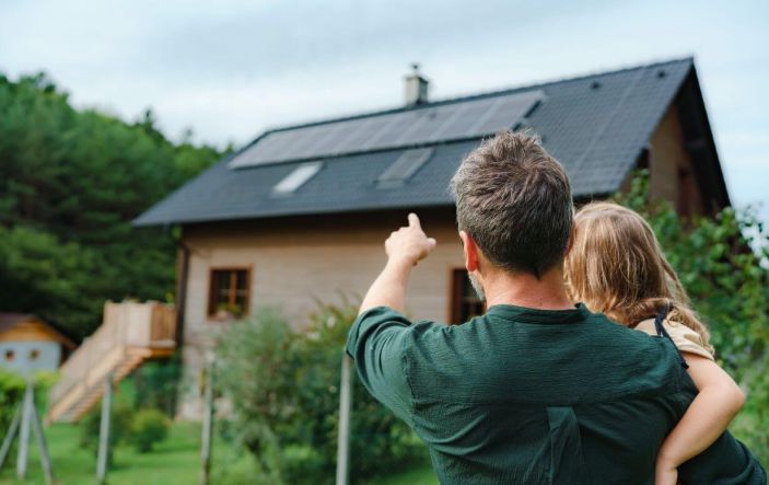 Homeowner with daughter pointing at home with solar panels