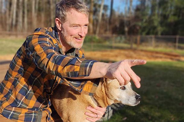 Rick Martin with dog pointing outside home Energy View